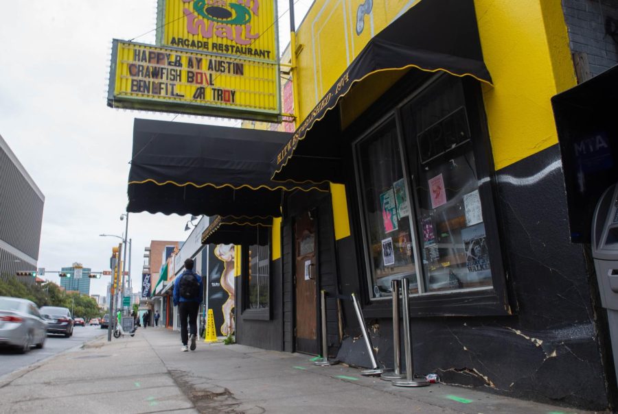 A student walks past Hole In The Wall on March 20, 2023. A car recently crashed into the bar, causing damage to the front of the building.